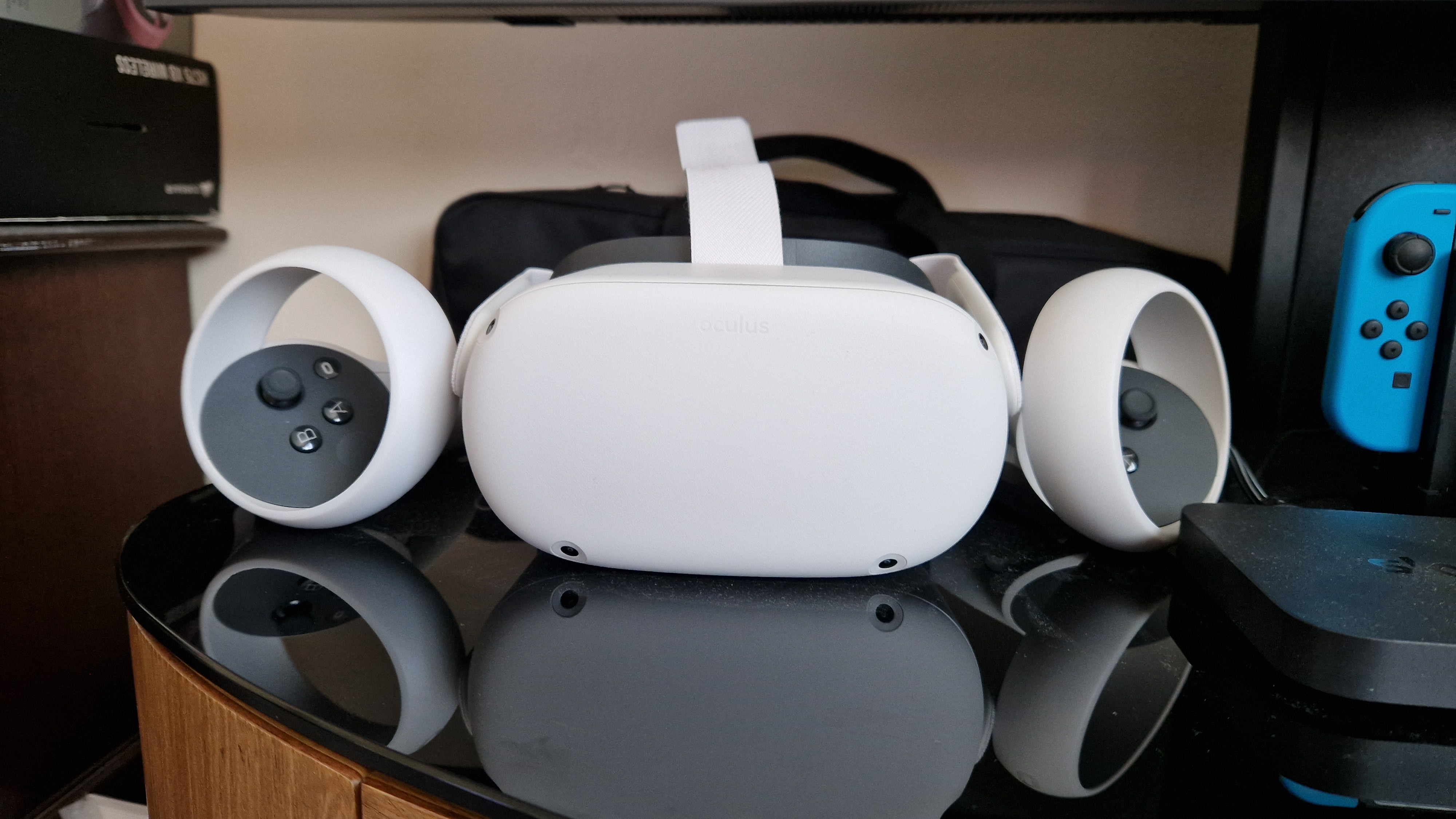 Meta Quest 2 headset and controllers front-on sat atop a TV stand