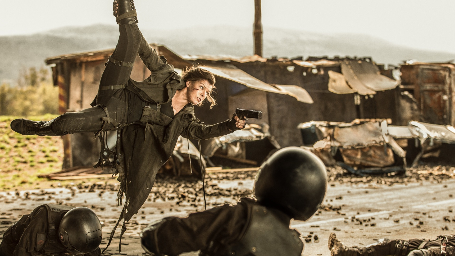 Milla Jovovich as Alice hanging in the air by her foot while shooting a handgun at enemies during Resident Evil: The Final Chapter